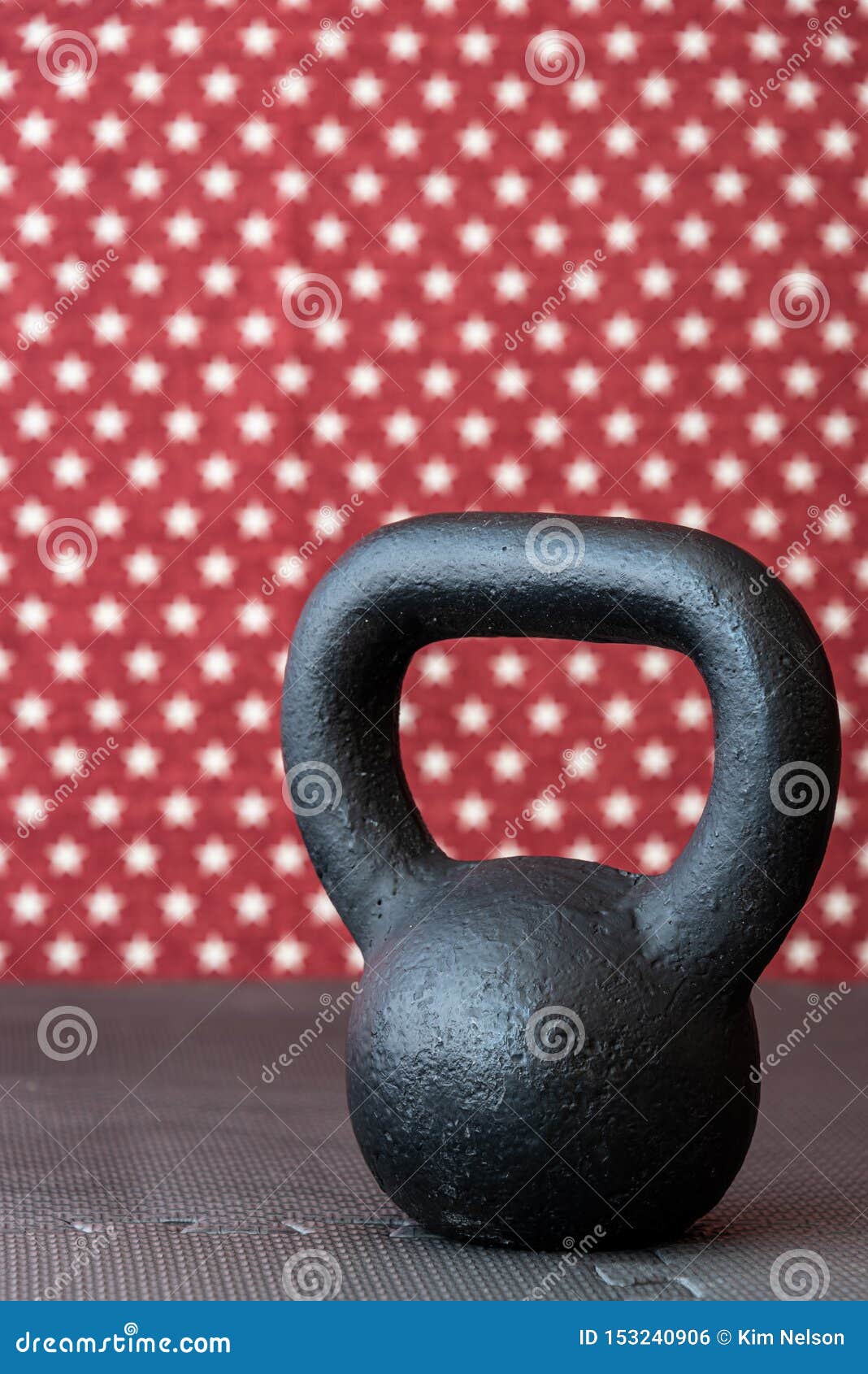 Rustic Black Kettlebell on a Black Rubber Mat Floor Against a Patterned
