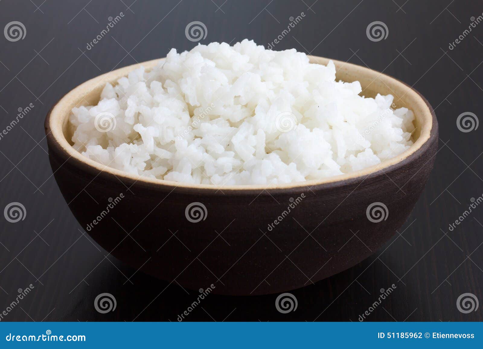 rustic bowl of cooked white rice on dark surface