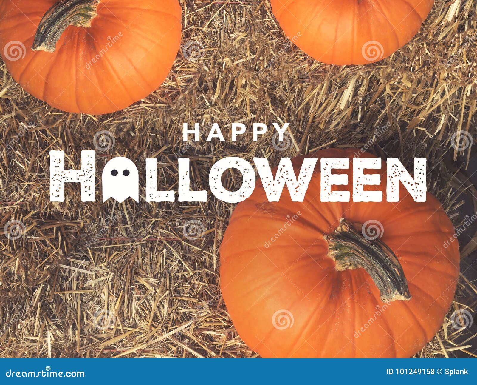 rustic happy halloween text with ghost icon over pumpkins and hay from directly above