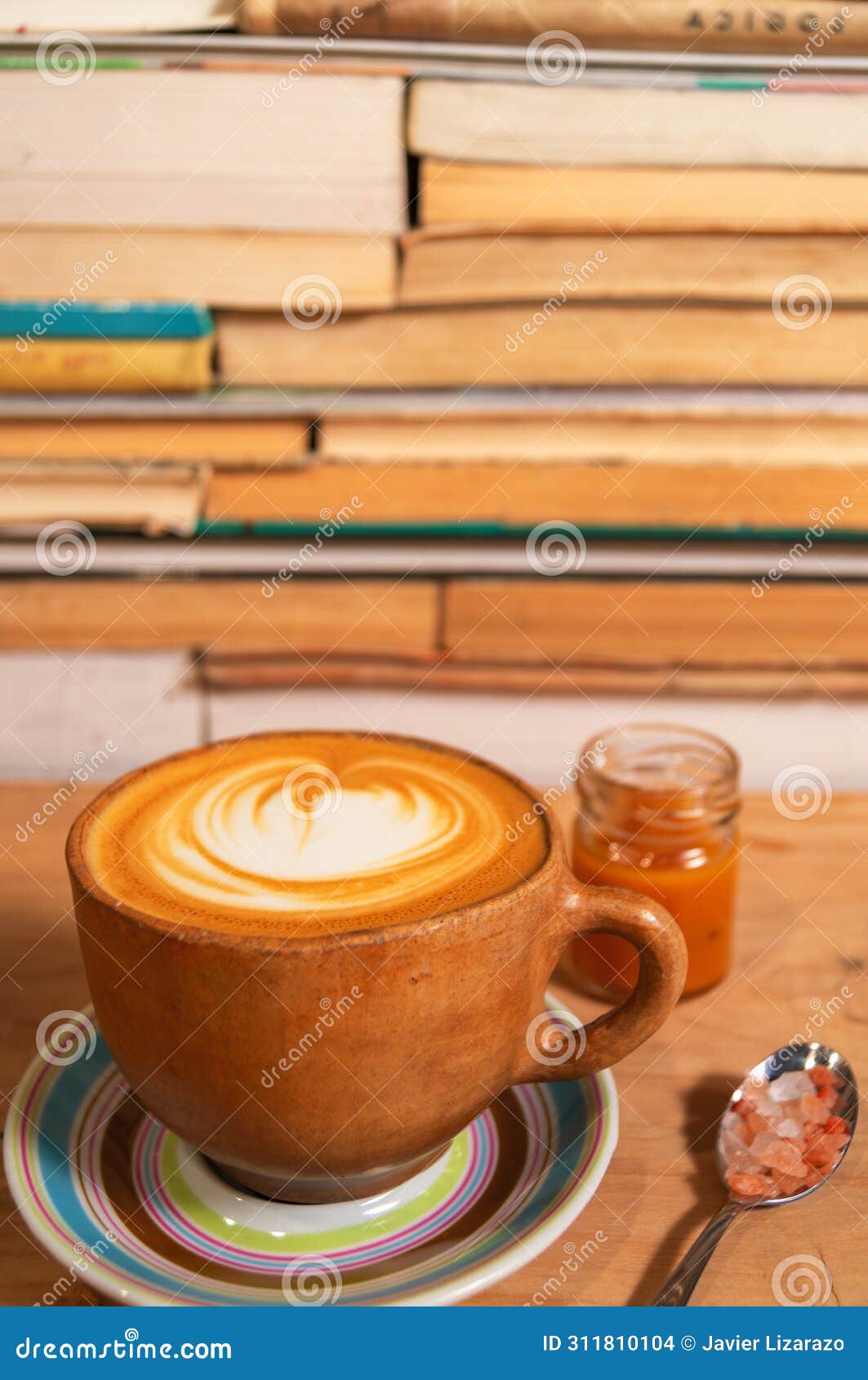 rustic ochre cappuccino mug with caramel and himalayan salt, d foam on plate, wood and book background - taza de capuchino r