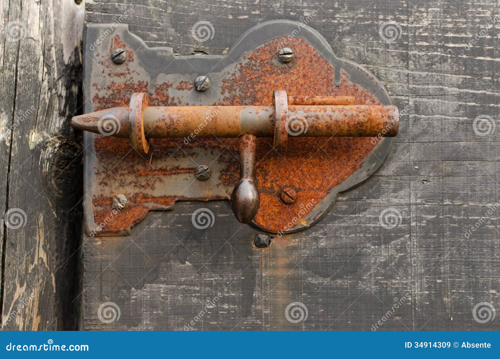 Old rusty barn latch in a wooden door.