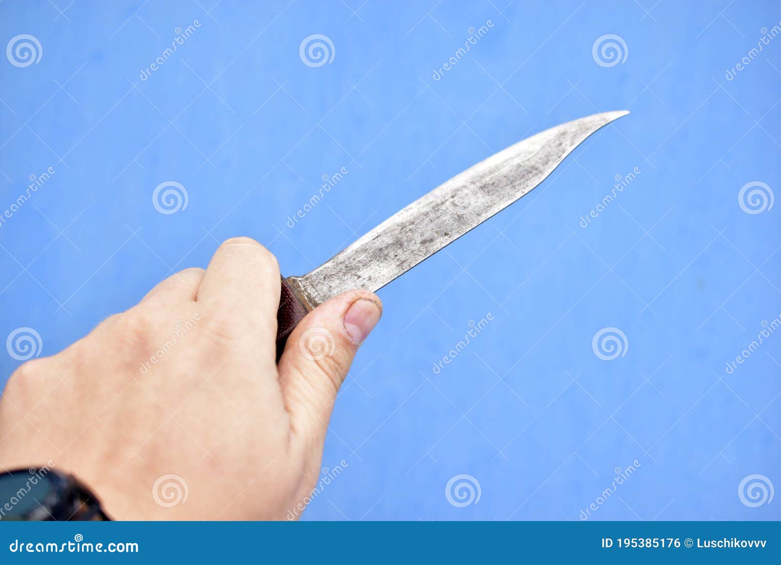 Rusty Criminal Sharp Knife in Hand on a Blue Background Stock Photo