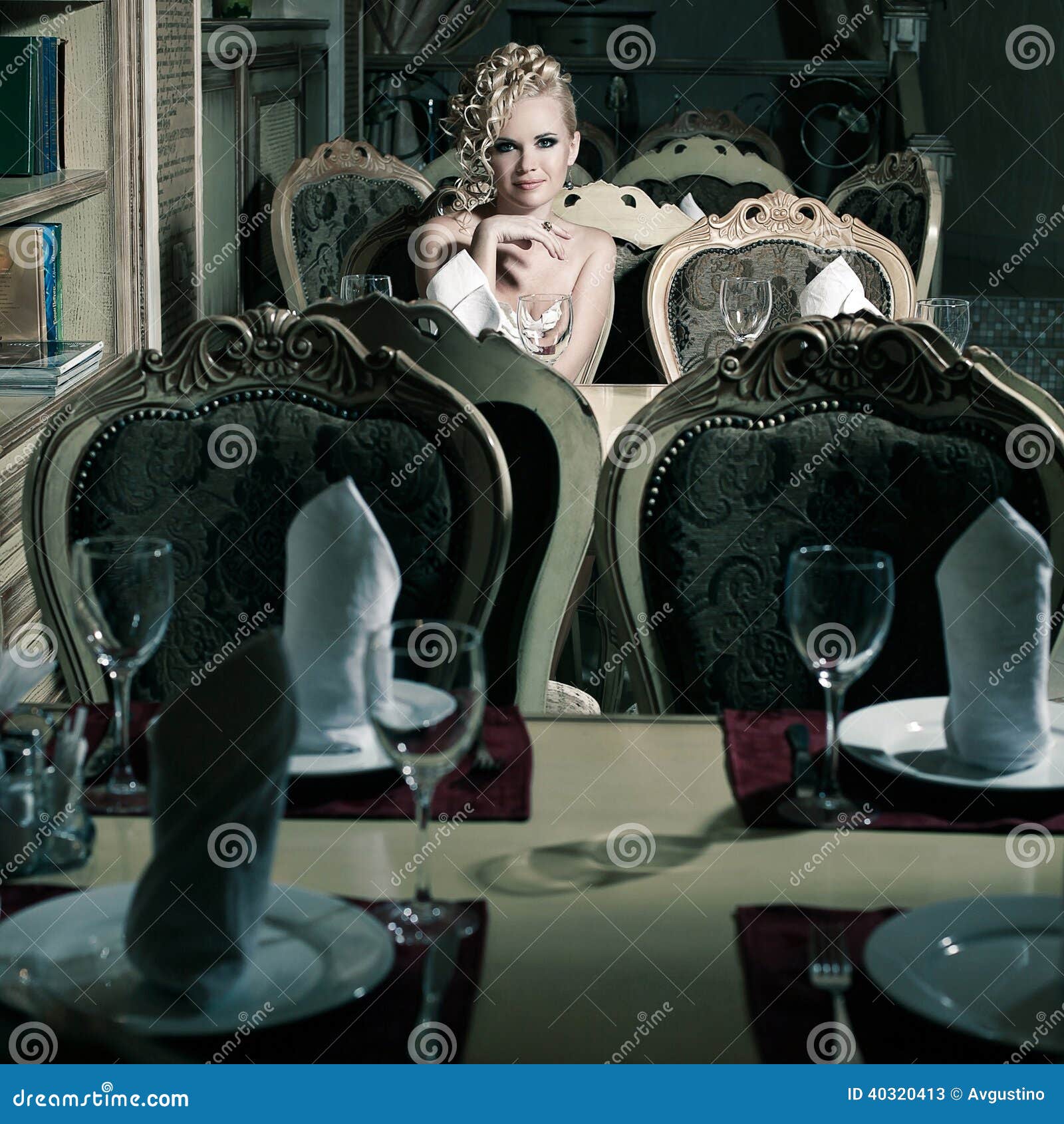 Rétro femme dans l'intérieur classique. Portrait d'une femme magnifique s'asseyant dans le restaurant avec l'intérieur classique luxueux. Style de vintage. Tir d'intérieur