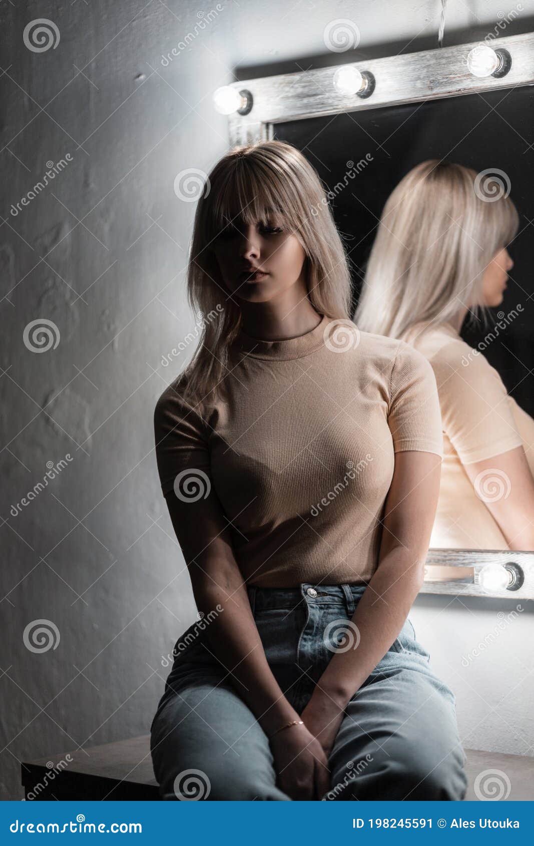 Söt Sexig, Vacker, Ung, Blond Kvinna Med Stilig Hårstil I En Moderiktig T-shirt I Blå Jeans Sitter Nära En Vintage Vit Fotografering för Bildbyråer  bild bild