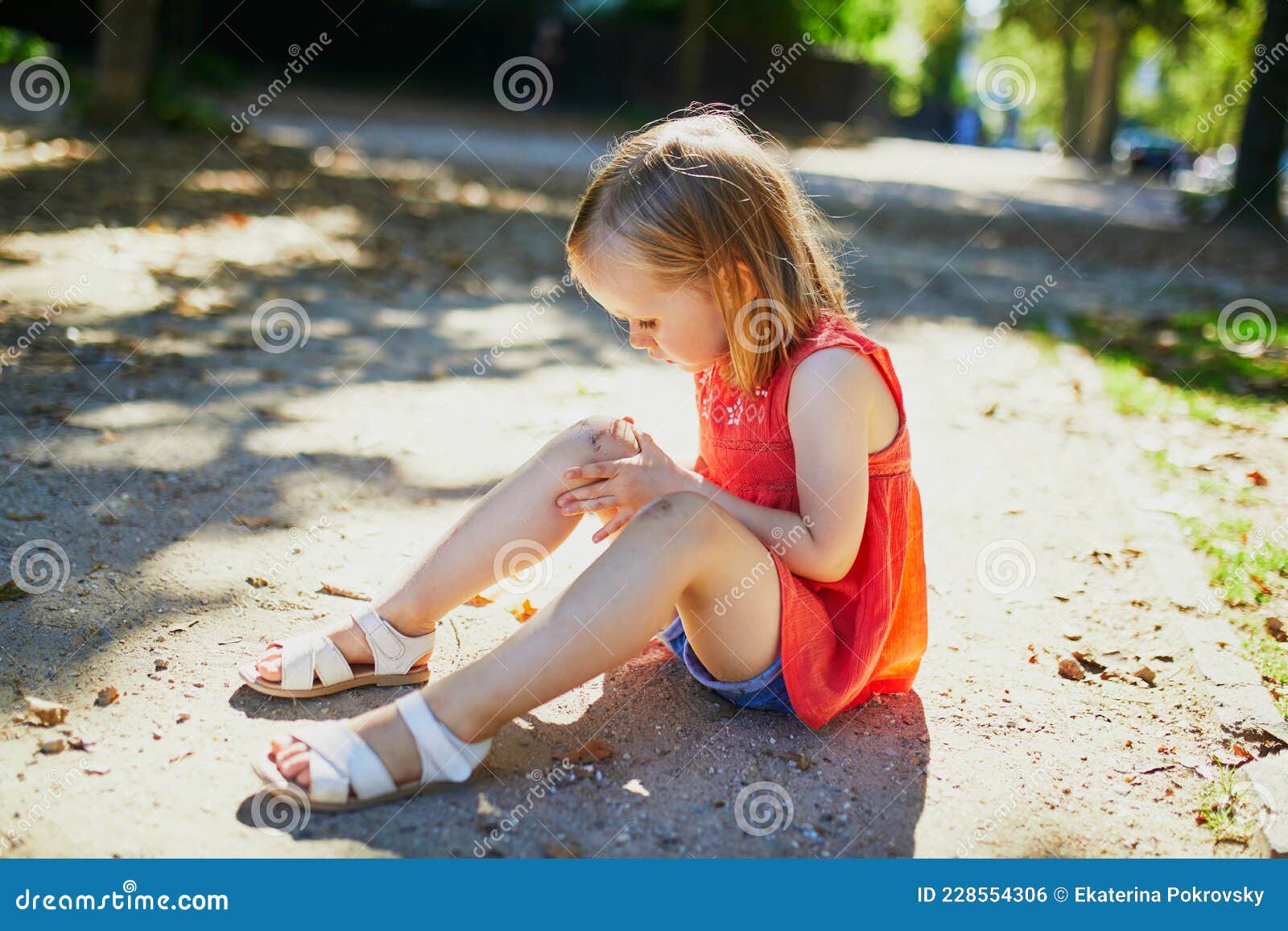 Süßes Kleines Mädchen, Das Nach Dem Sturz Auf Dem Boden Sitzt Stockfoto -  Bild von traurig, knie: 228554306