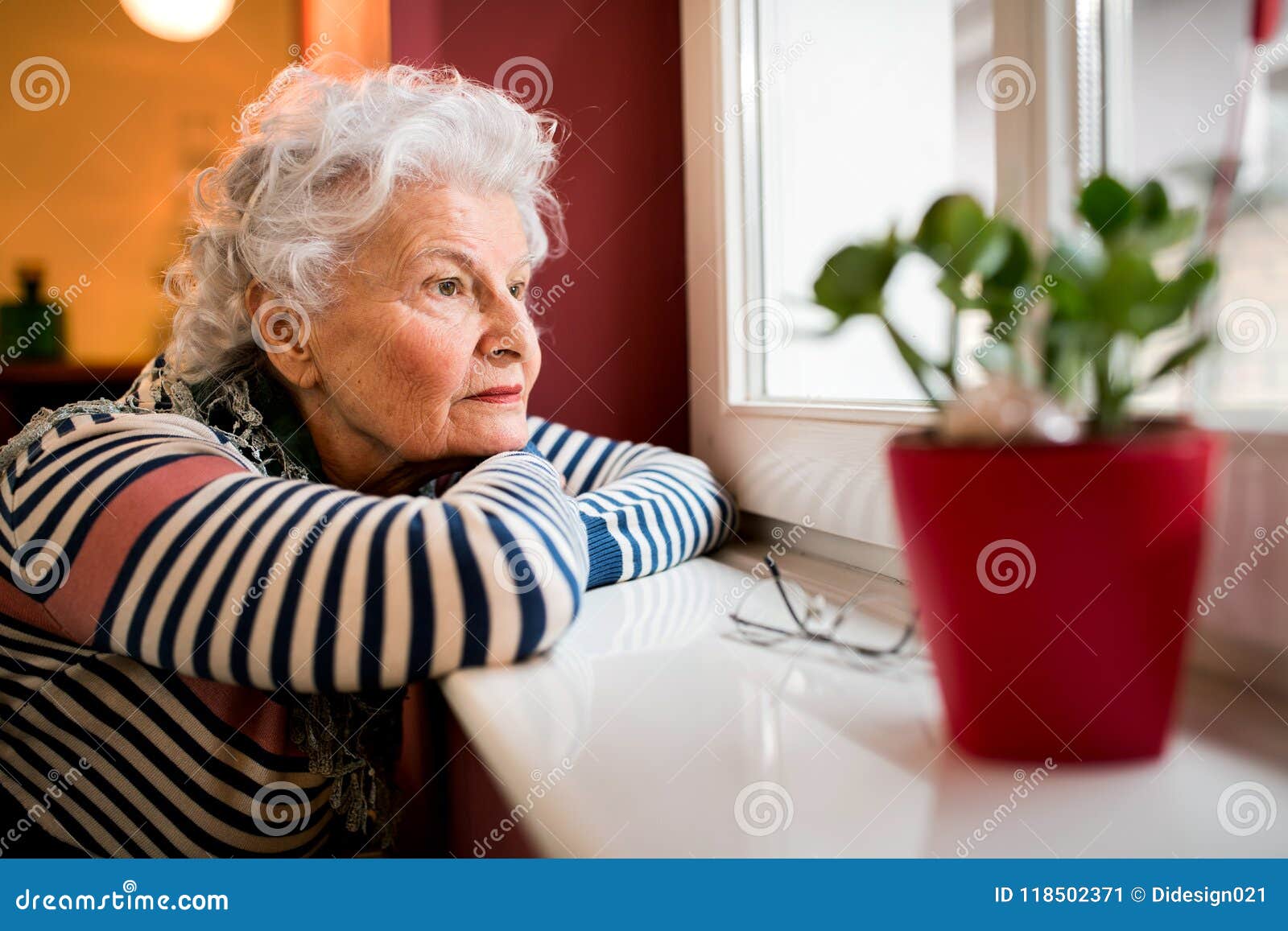 sad alone senior woman looking through window