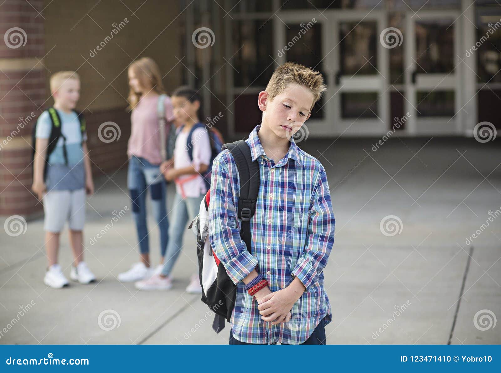 sad boy feeling left out, teased and bullied by his classmates