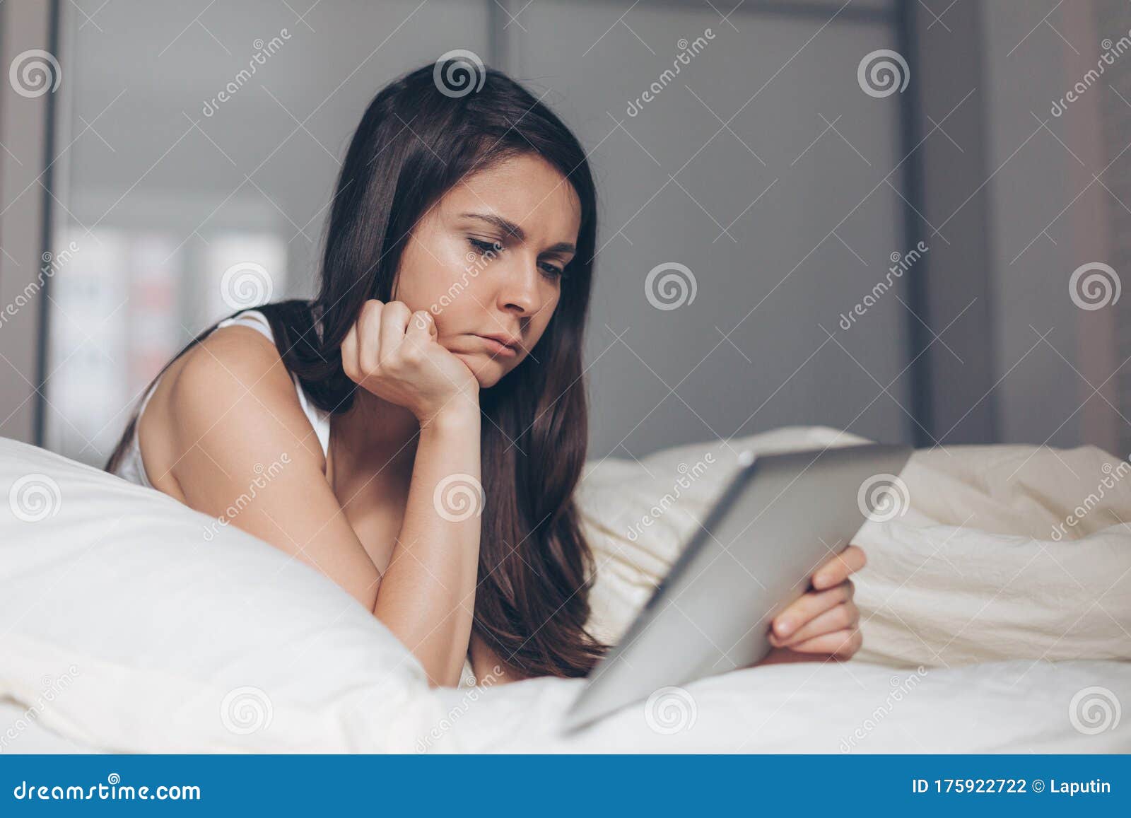 Sad Girl Looks Into Tablet In Hands On Bed Stock Photo Image Of