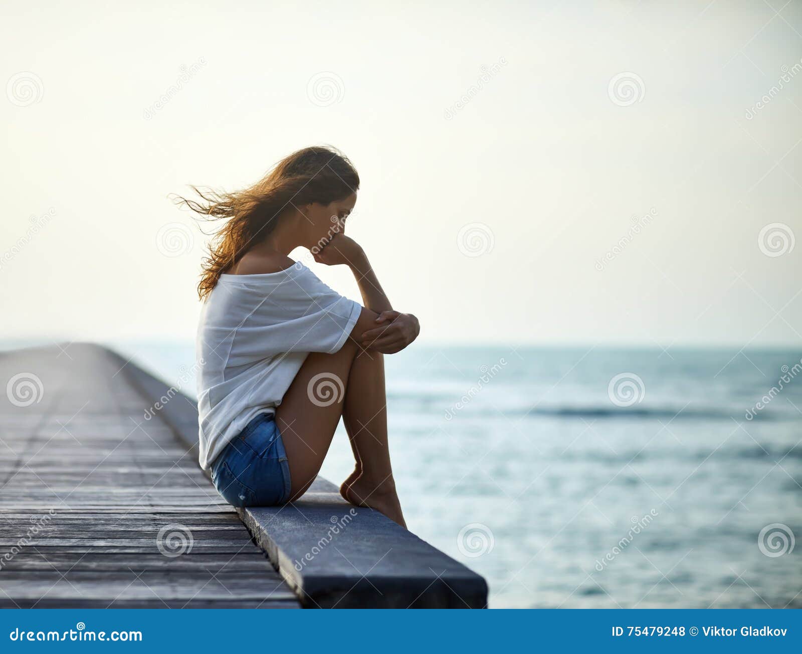 sad lonely beautiful woman sitting on the pier