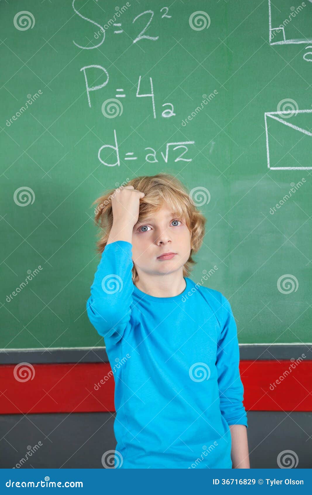 Sad Schoolboy Standing Against Board In Classroom Sad Schoolboy Standing Against Board In Classroom Stock