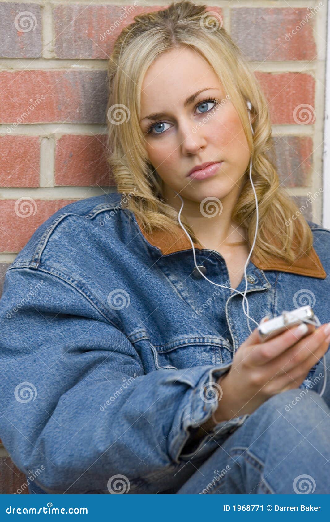 Sad Songs. A beautiful young woman leaning against a wall and listening to an mp3 player with a sad look on her face