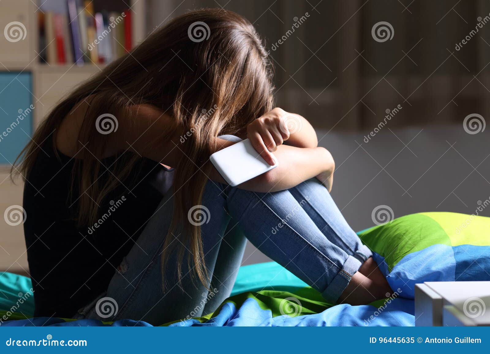 sad teen with a phone in her bedroom