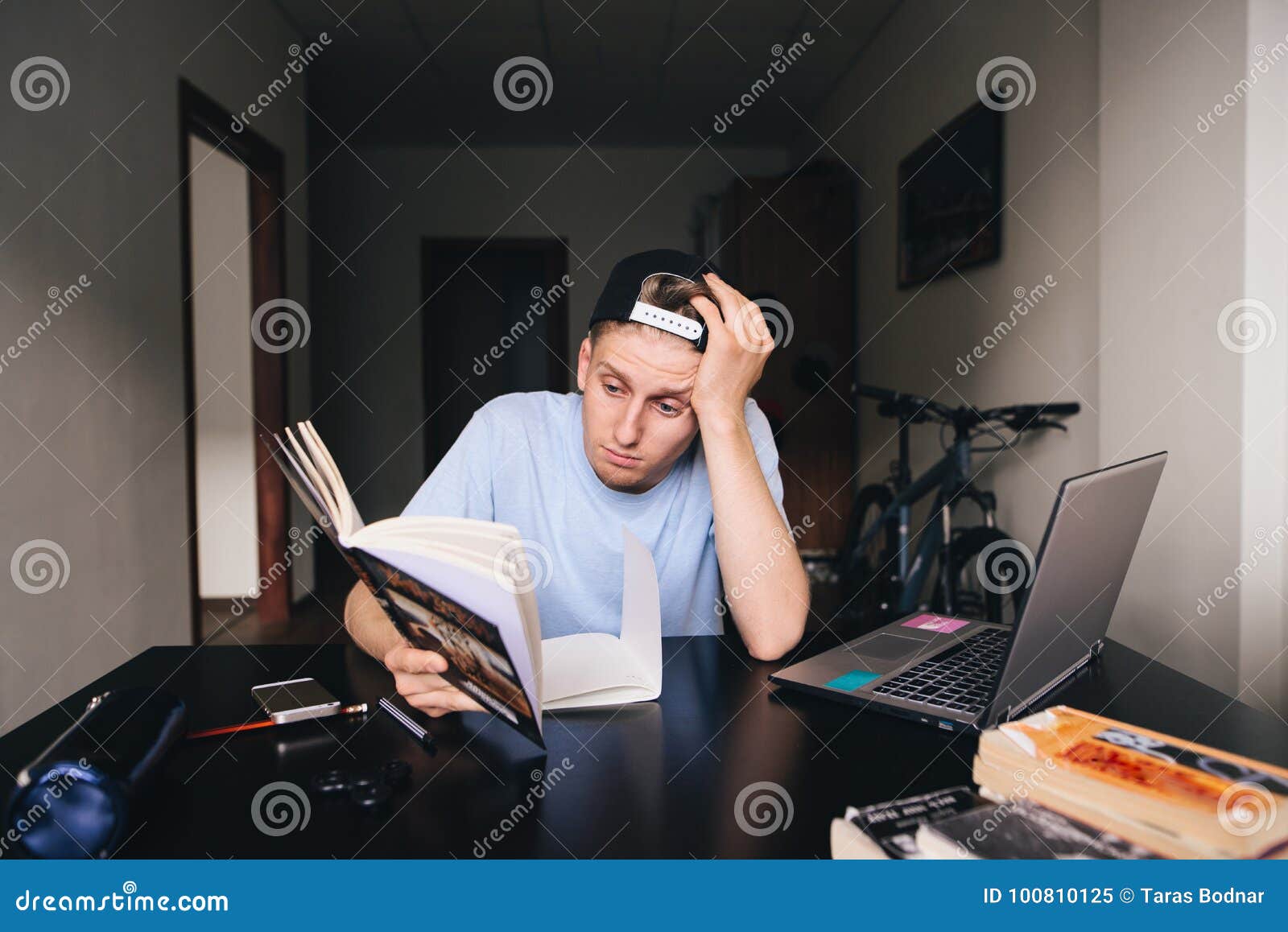 sad-teen-reads-book-desk-near-computer-his-room-teaching-home-student-does-not-want-to-read-100810125.jpg