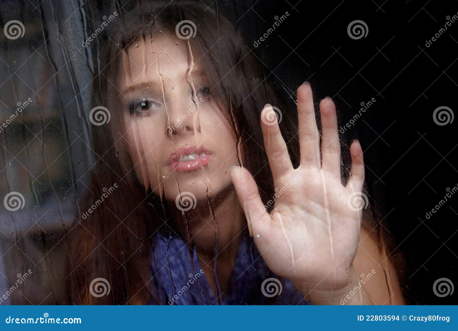 sad woman behind wet window
