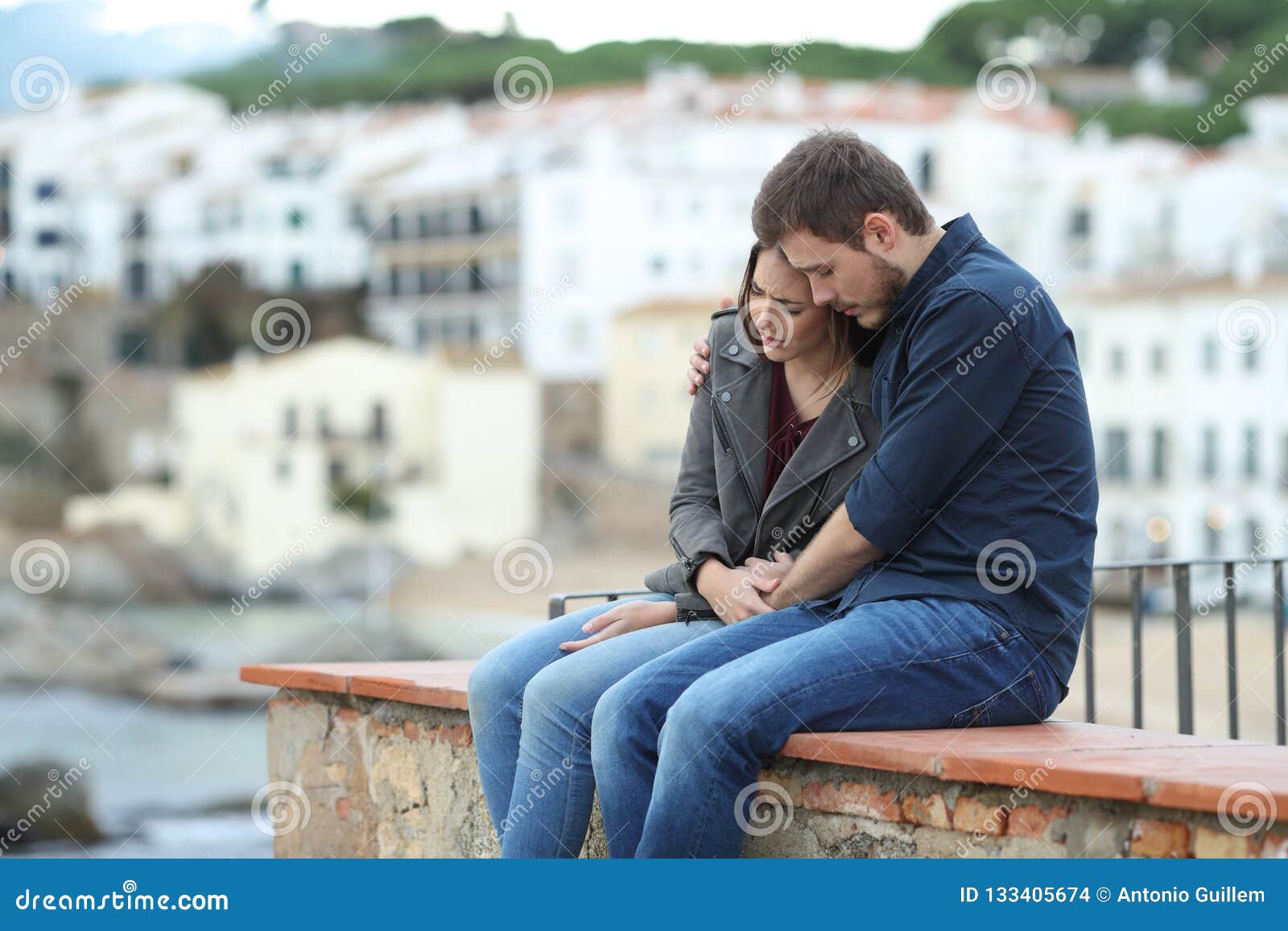sad woman and man comforting her on a ledge