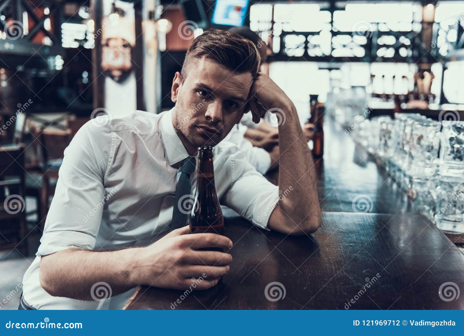 Sad Young Man with Bottle of Beer Sitting in Bar. Stock Photo - Image ...