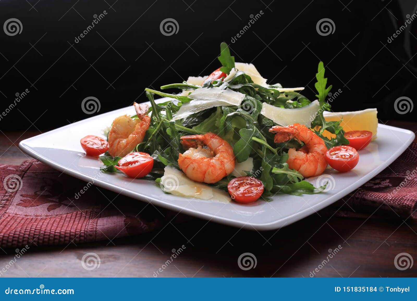 salad with arugula and cherry tomatoes with shrimp, slices of lemon and parmesan