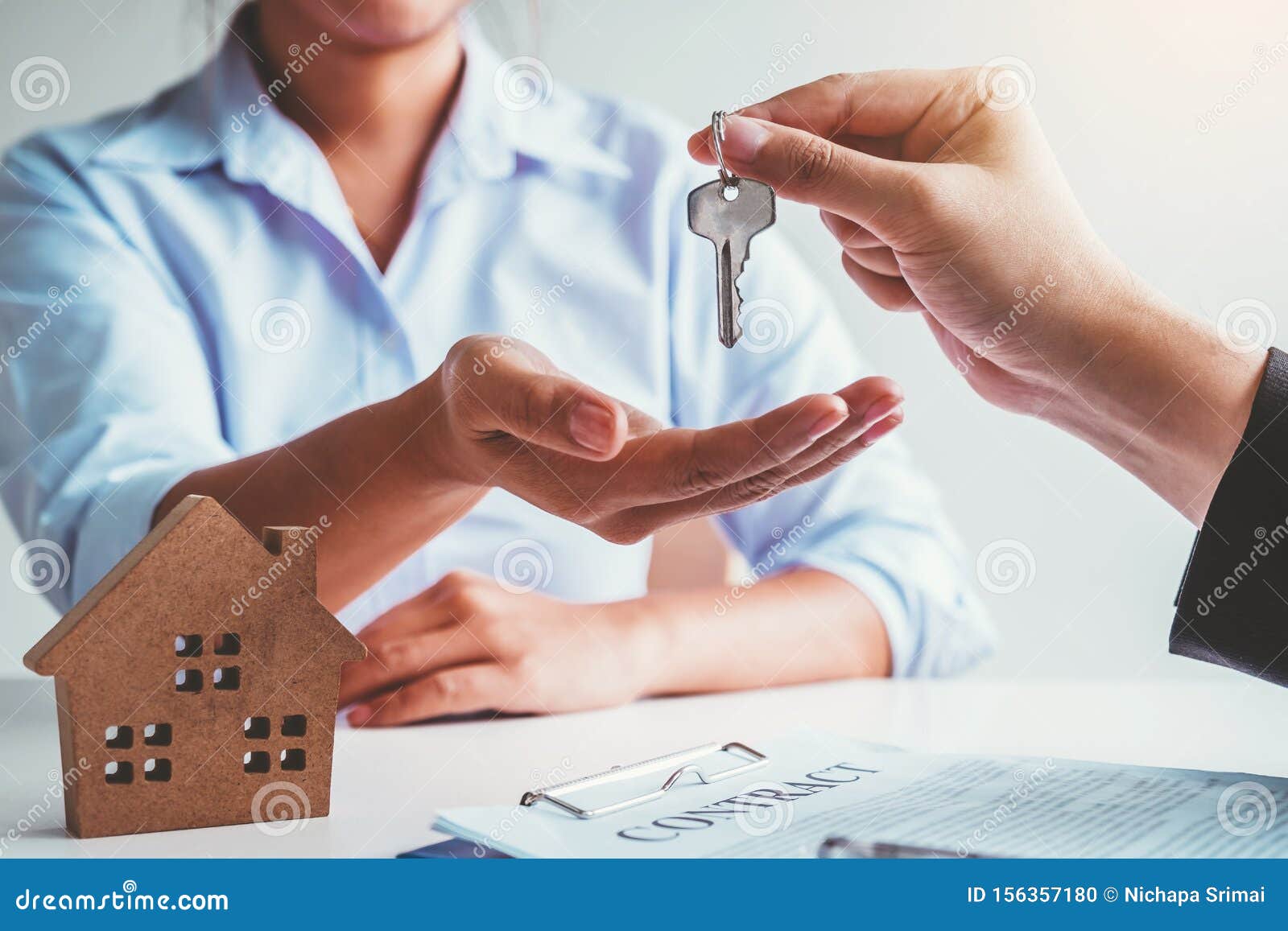 sale agent giving house keys to woman customer and sign agreement documents for realty purchase