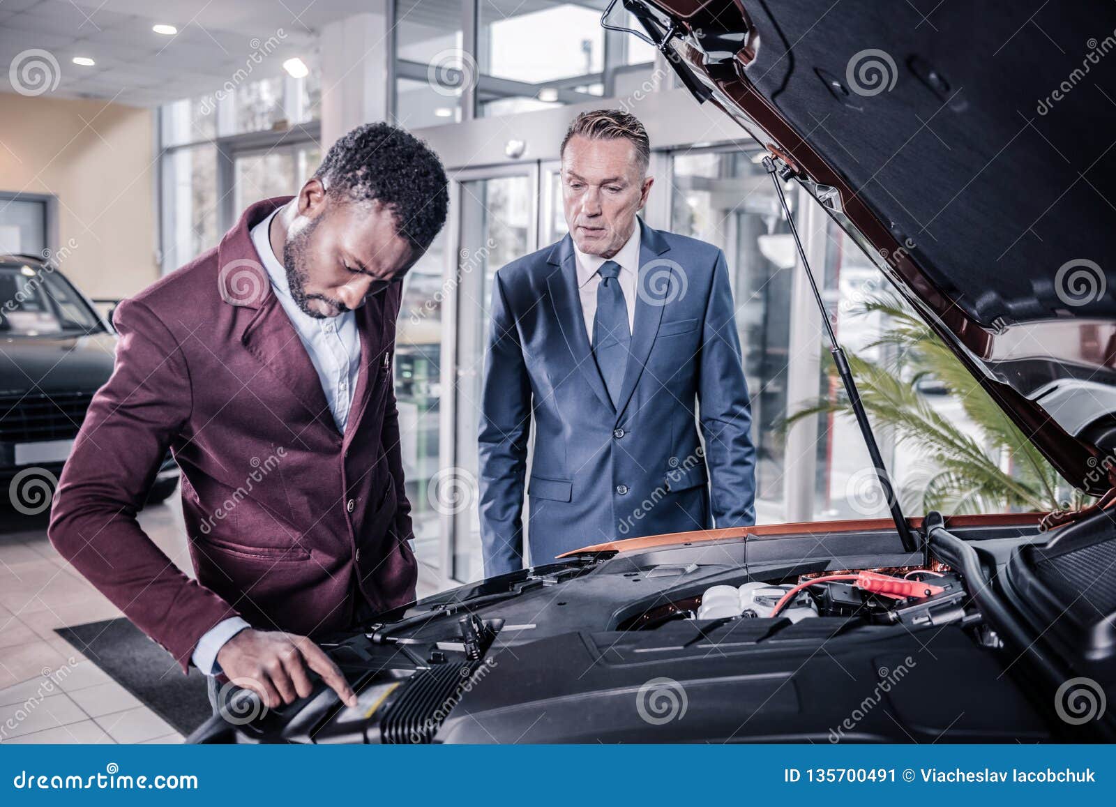 Sales Manager of Car Salon Opening Front Trunk Describing Car for