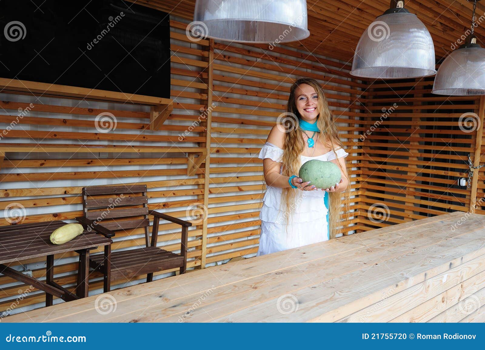 Salesgirl con una zucca. Assistente di negozio che offre una zucca