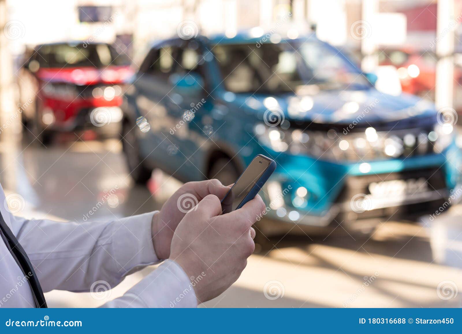 Salesman Using Mobile Smart Phone at Dealer Showroom Stock Photo