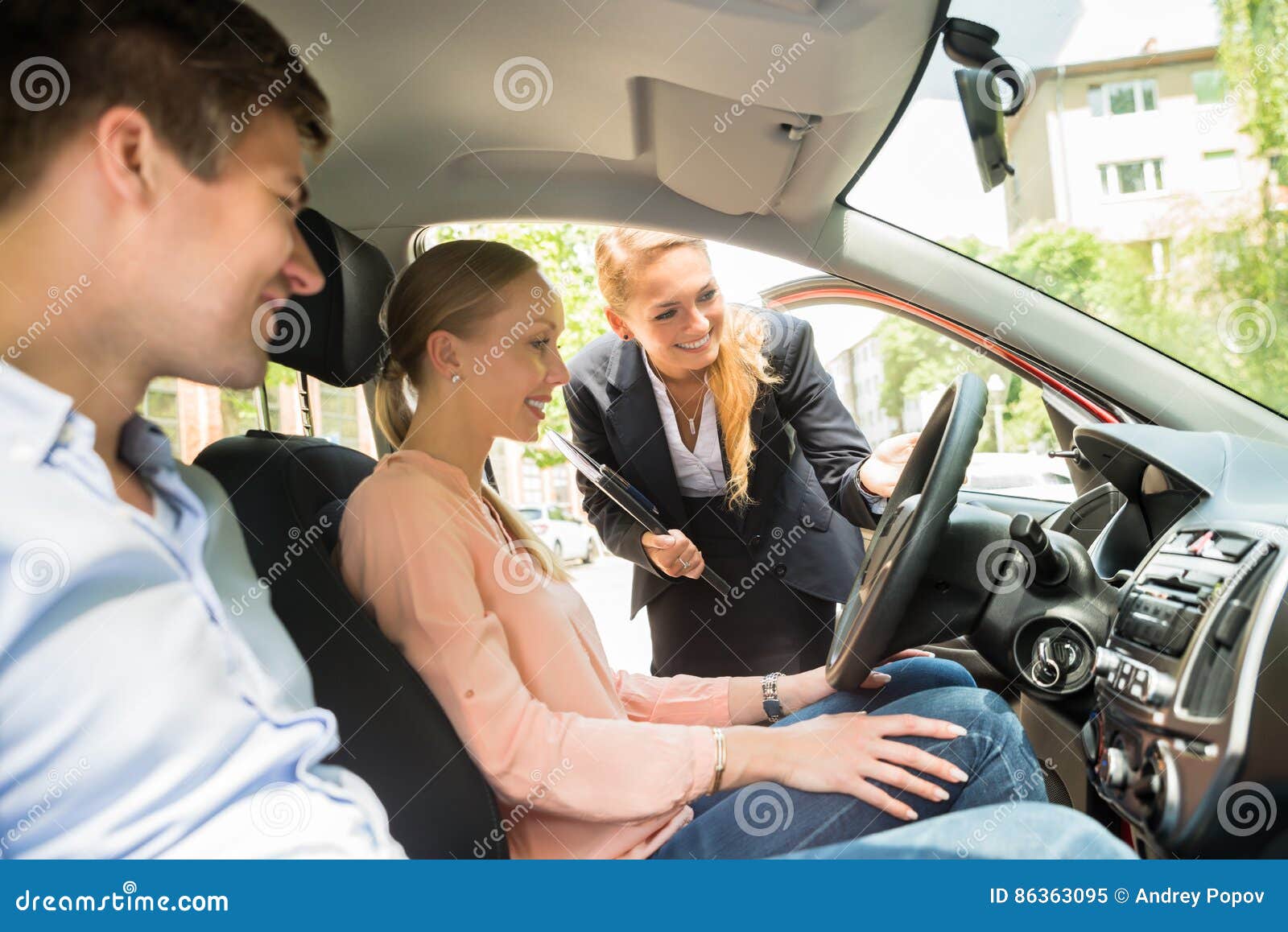 saleswoman showing car to couple
