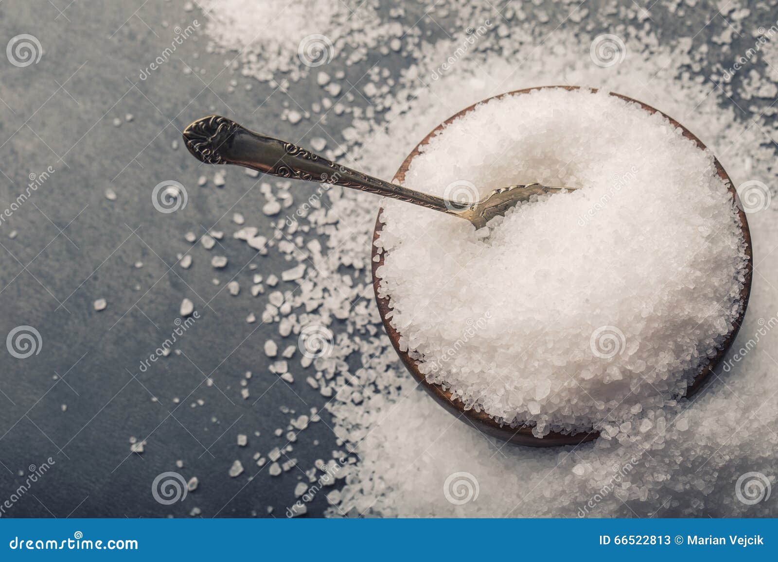 salt. coarse grained sea salt on granite - concrete stone background with vintage spoon and wooden bowl