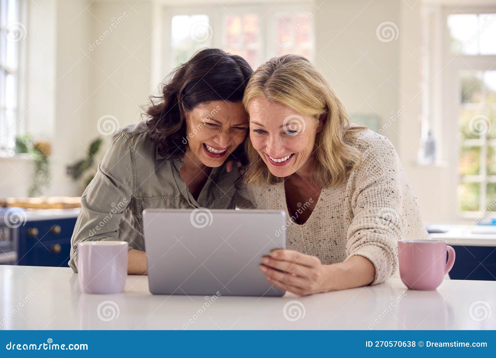 Same Sex Mature Female Couple Using Digital Tablet at Home To Stream Movie Stock Photo