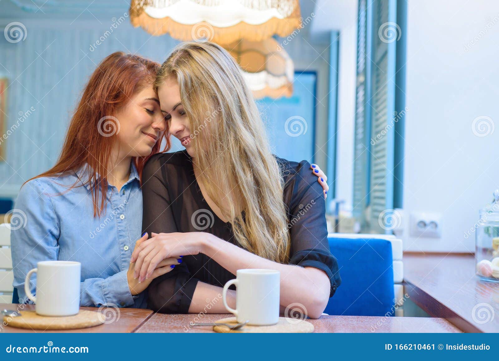 Same Sex Relationships Happy Lesbian Couple Sitting In A Cafe Girls Gently Hold Hands And