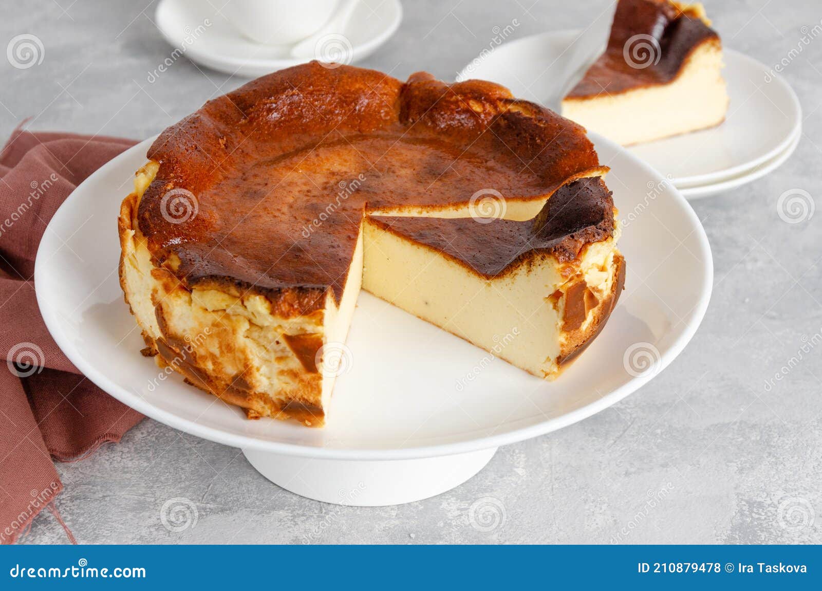 san sebastian cheesecake on top on a white plate on a gray concrete background. traditional spanish dessert.