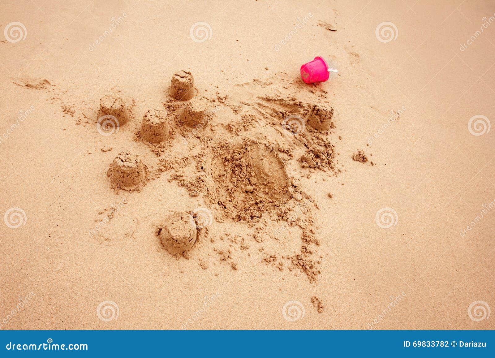 Sandslottar för barn` s på en strand eller i sandlåda med den lilla rosa plast- hinken