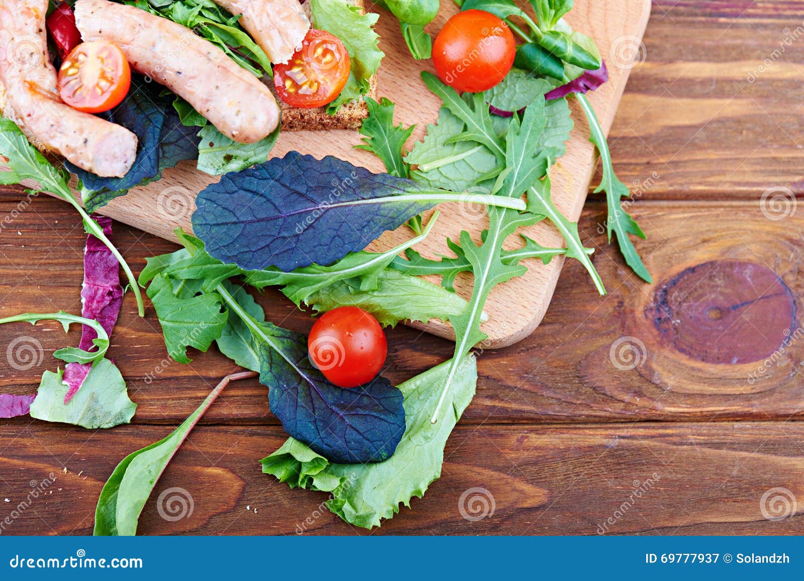 Hoogste mening bij sandwiches op de houten lijst Met worsten, salade, tomaten en Spaanse peperdocument op een houten achtergrond