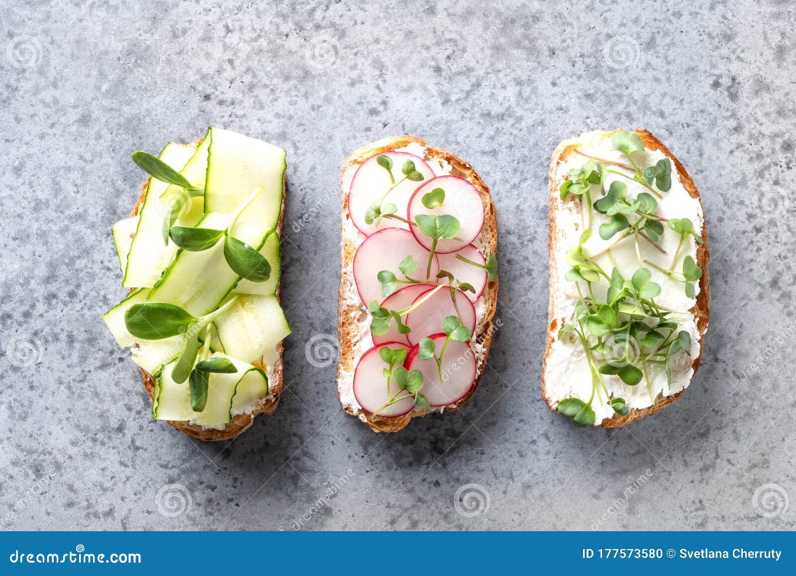 sandwiches with sundries tomatoes, fresh radish, microgreens, cream cheese on grey background.
