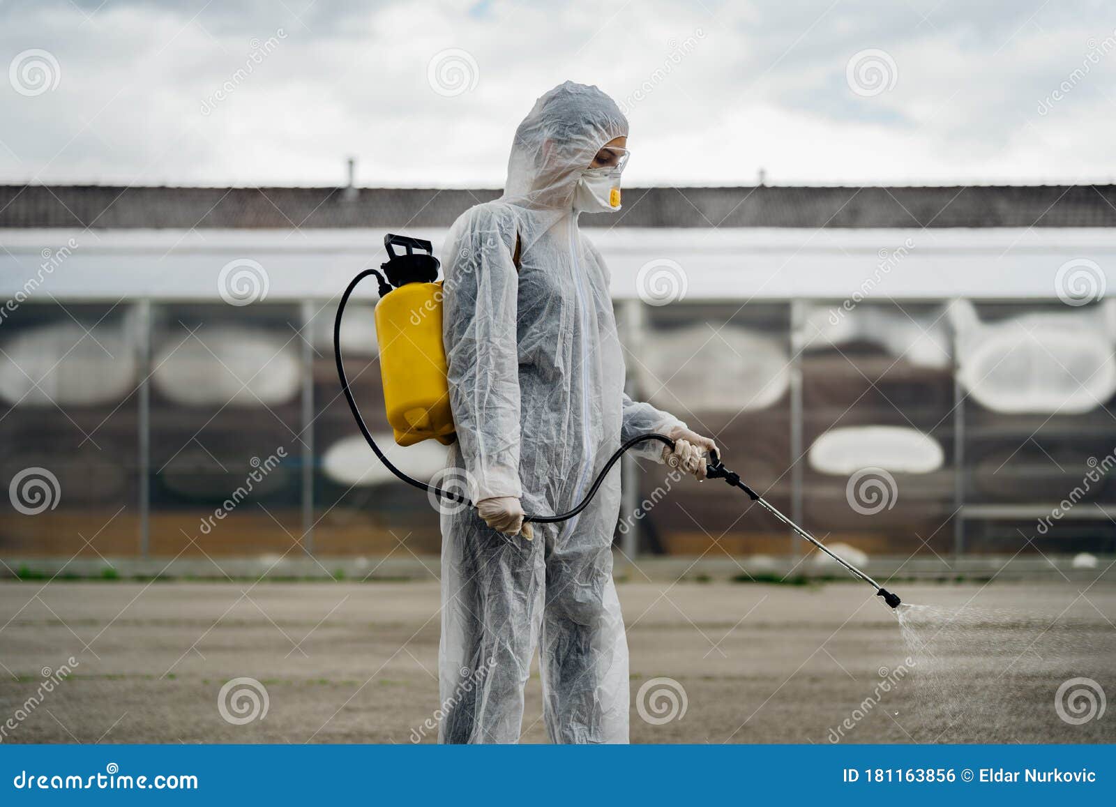 sanitation worker in hazmat protection suit and n95 mask with chemical decontamination sprayer tank.disinfecting streets and