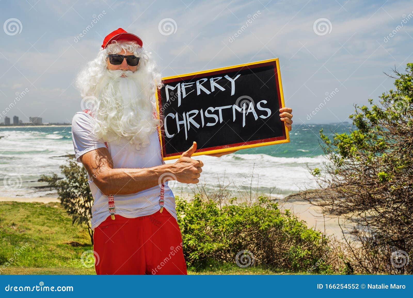 Santa Claus Holds Gift Boxes with the Ocean on Backgraund Photo - of beach, travel: 166254552
