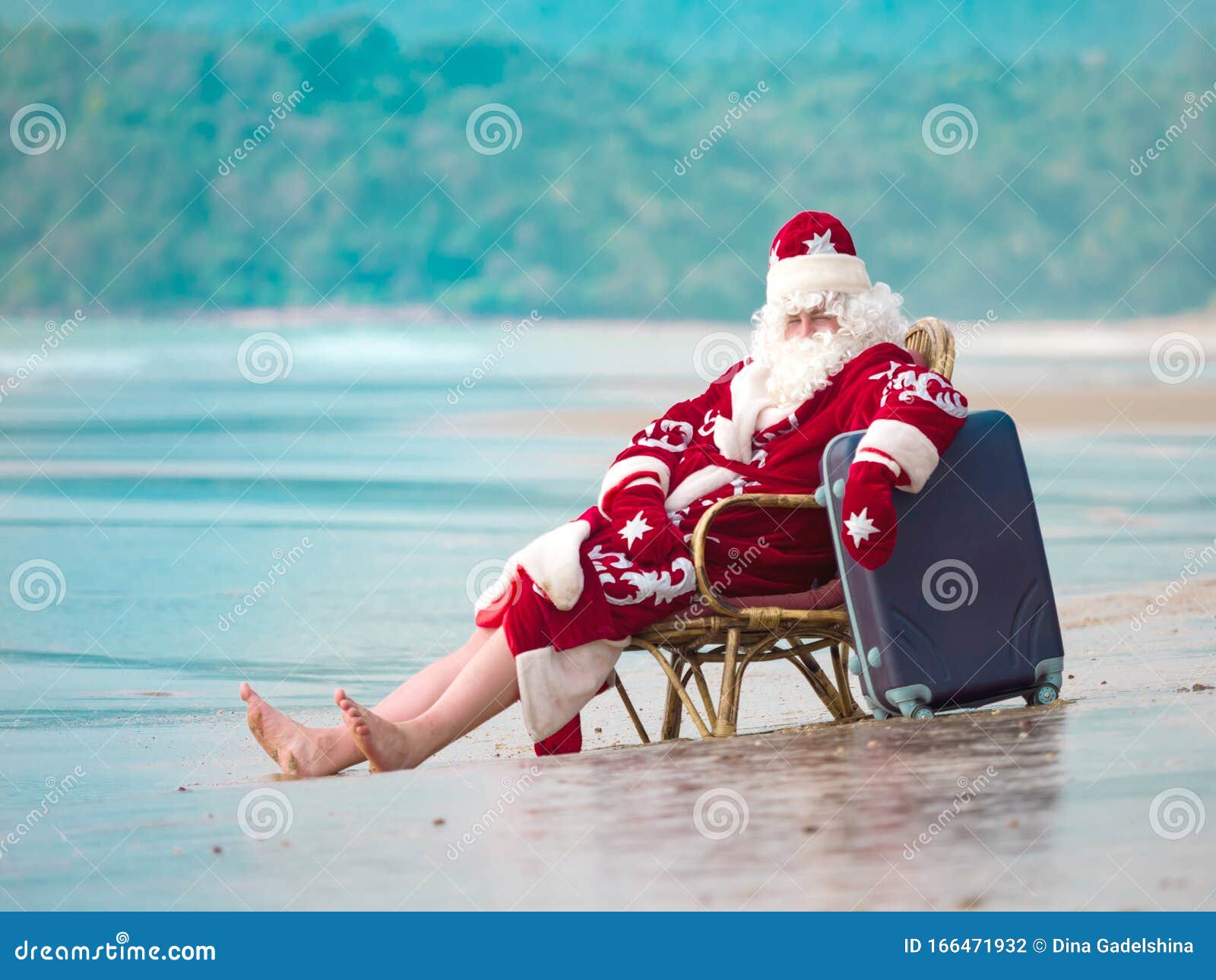 Santa Claus in Red Clothes with a Suitcase Sits in a Chair by the Ocean ...