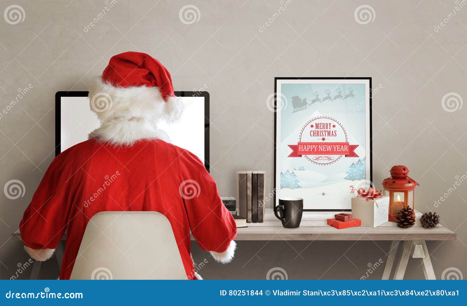 santa claus surfs the web on laptop. on his table is lantern, picture, gifts, books and a cup of hot tea