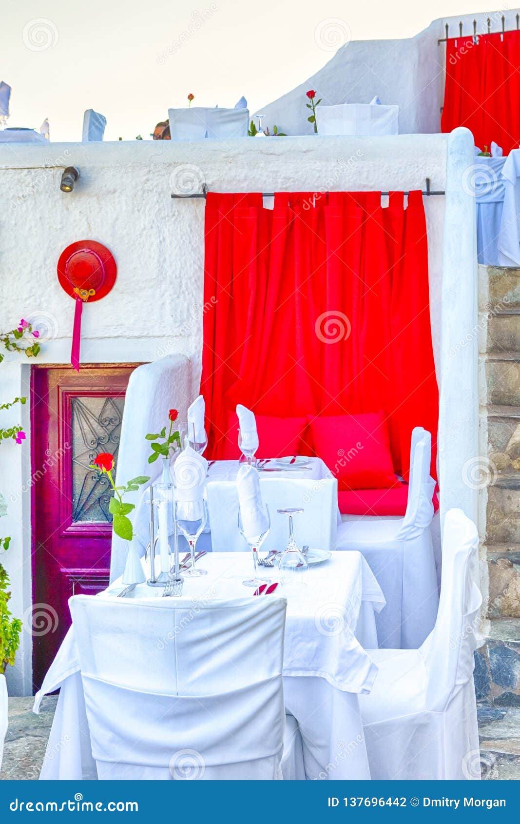 santorini island classic open air restaurant with served table and red curtains