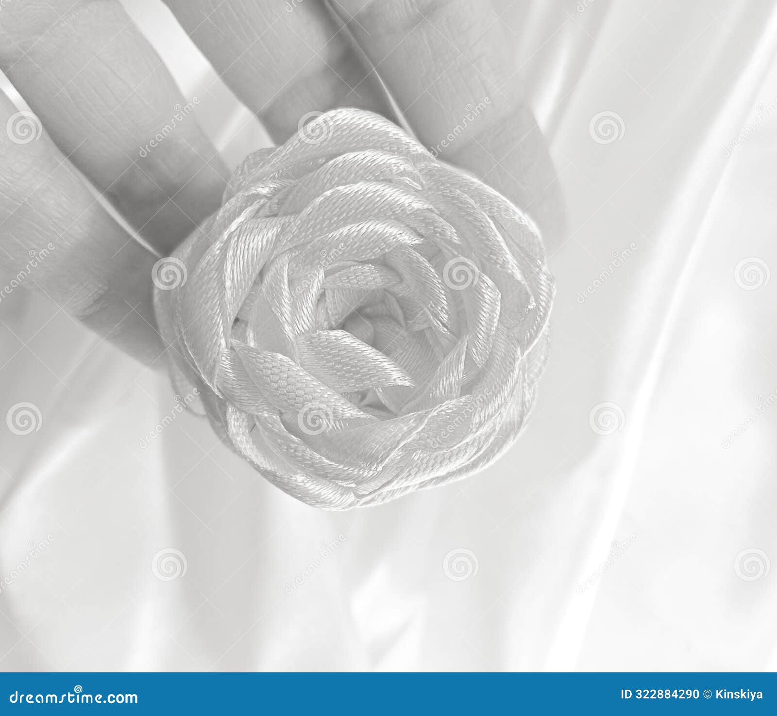 satin rose ribbon embroidery in hand fingers. monochrome textile flower decor .