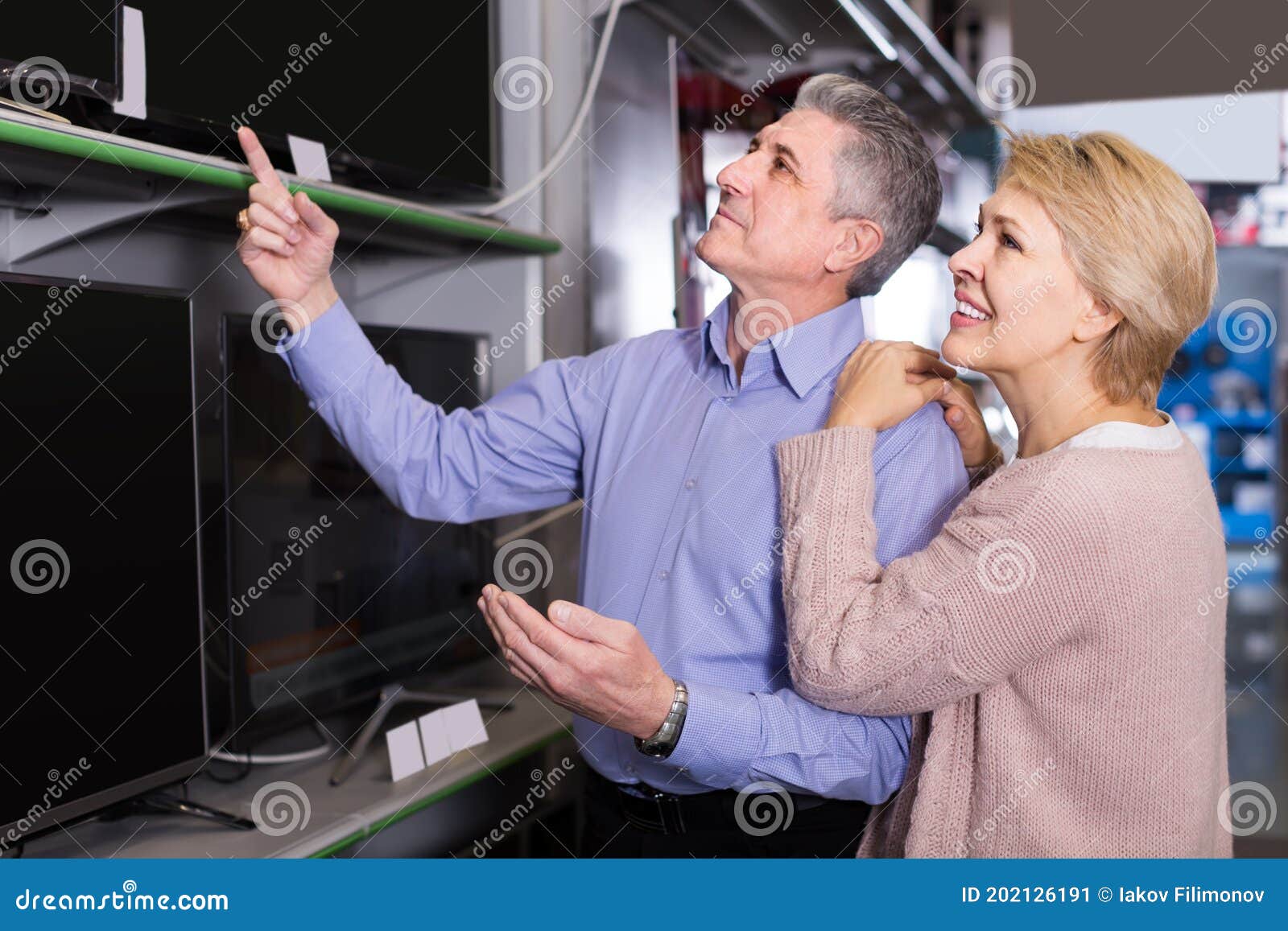 satisfied husband and wife choose for themselves tv in center of electronics