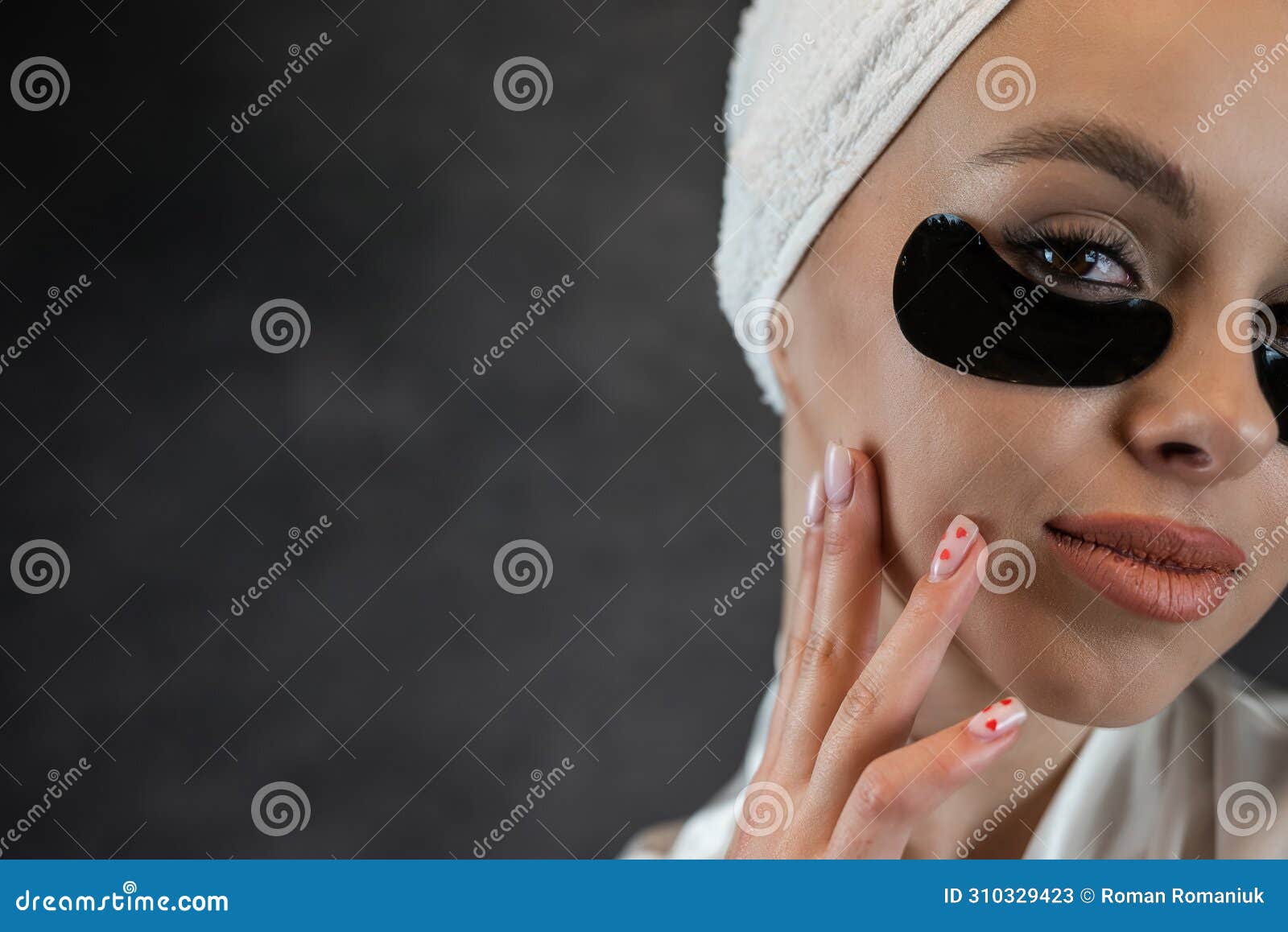 satisfied woman in white towel applying eye patches for puffiness, wrinkles