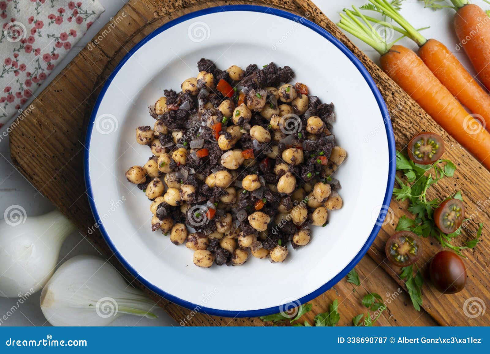 sautÃ©ed chickpeas with black pudding and vegetables. top view table with decoration.