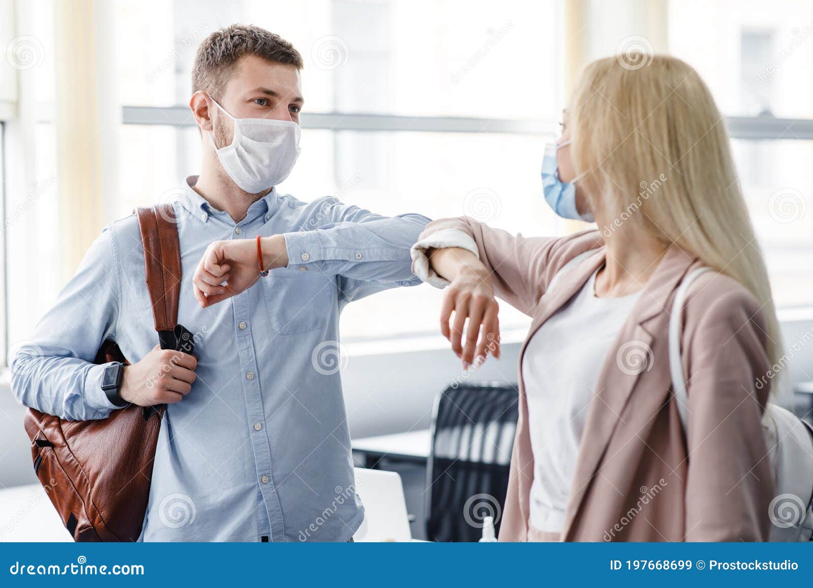 say hello, social distance and return to work after quarantine. millennial man and woman in protective masks are touched