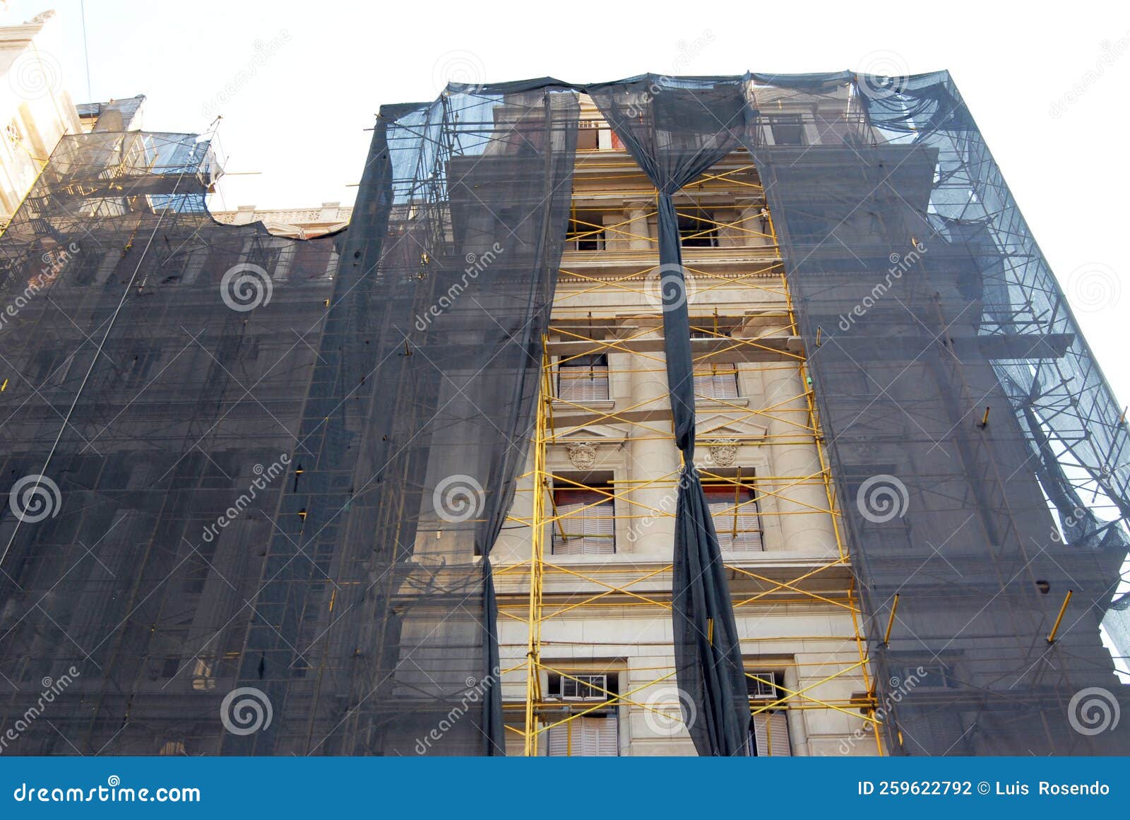 scaffolding and netting covering the facade of a tall building being renovated