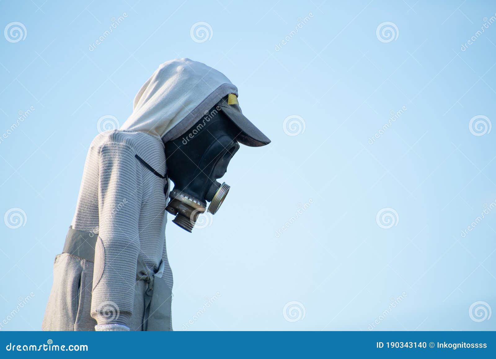 scarecrow with gas mask against blue sky