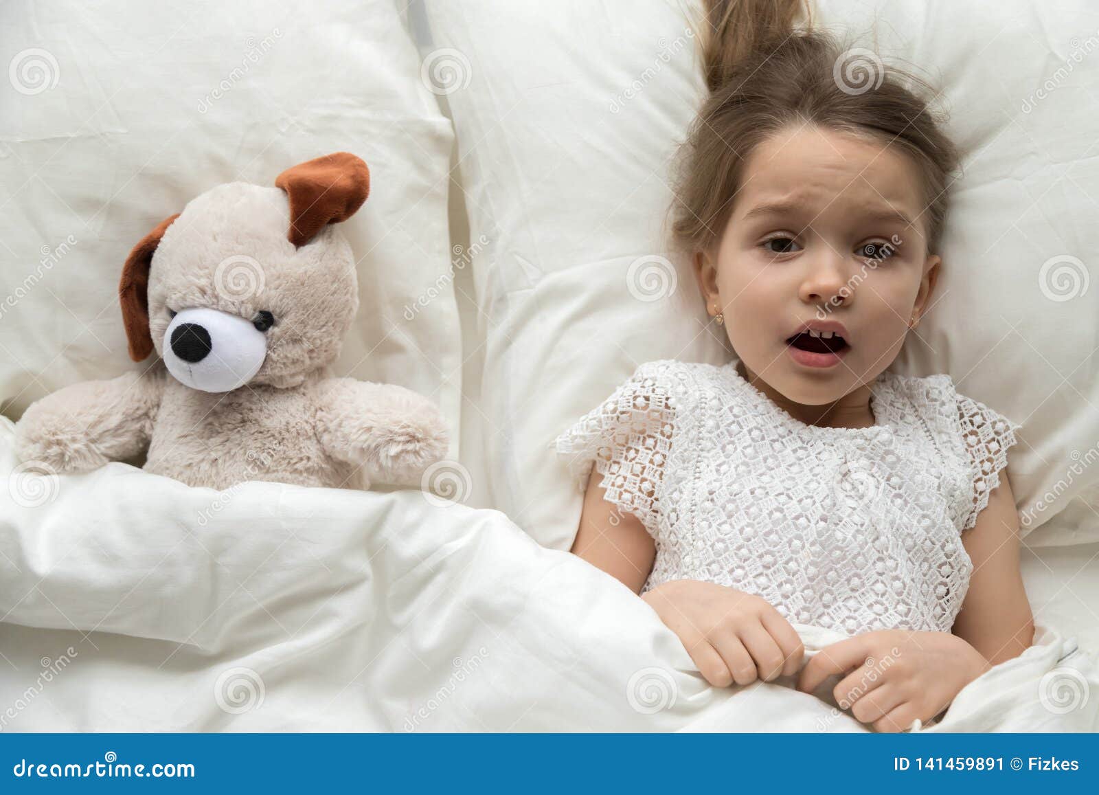 scared child lying in bed with toy afraid of nightmare