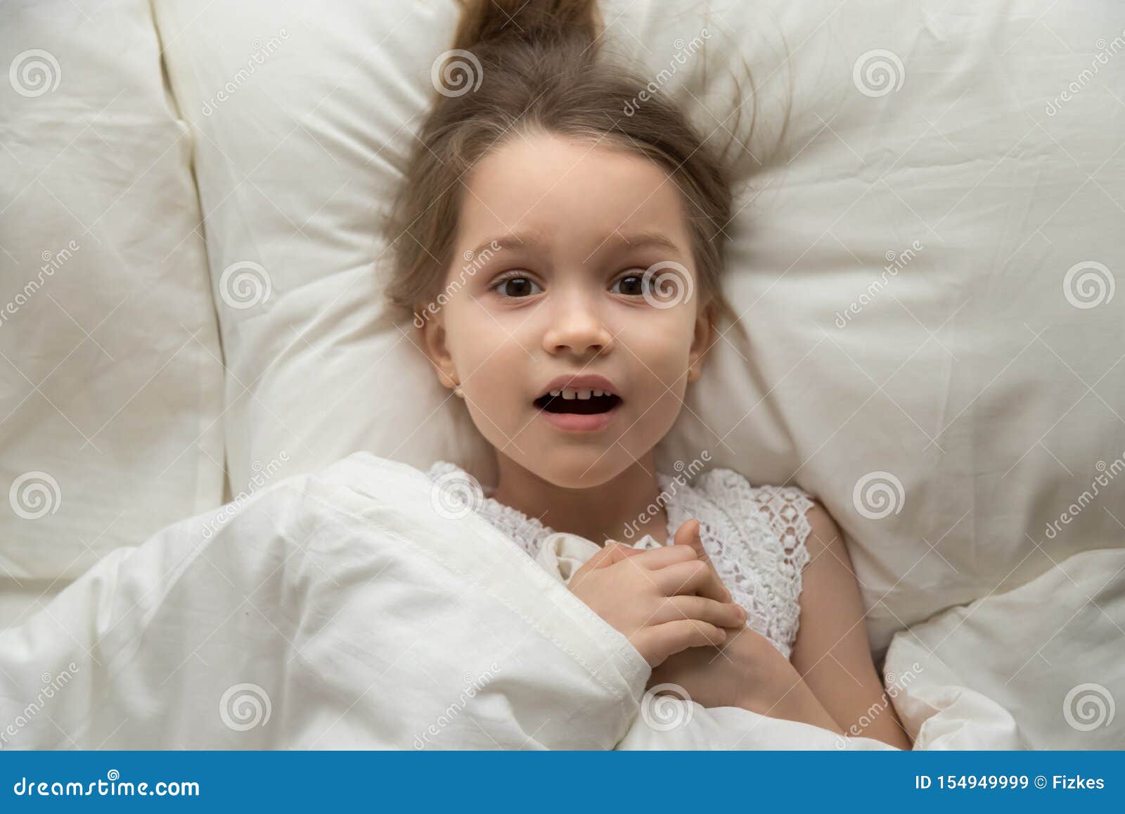 Above View Frightened Girl Lying On Bed Looking At Camera Stock Image