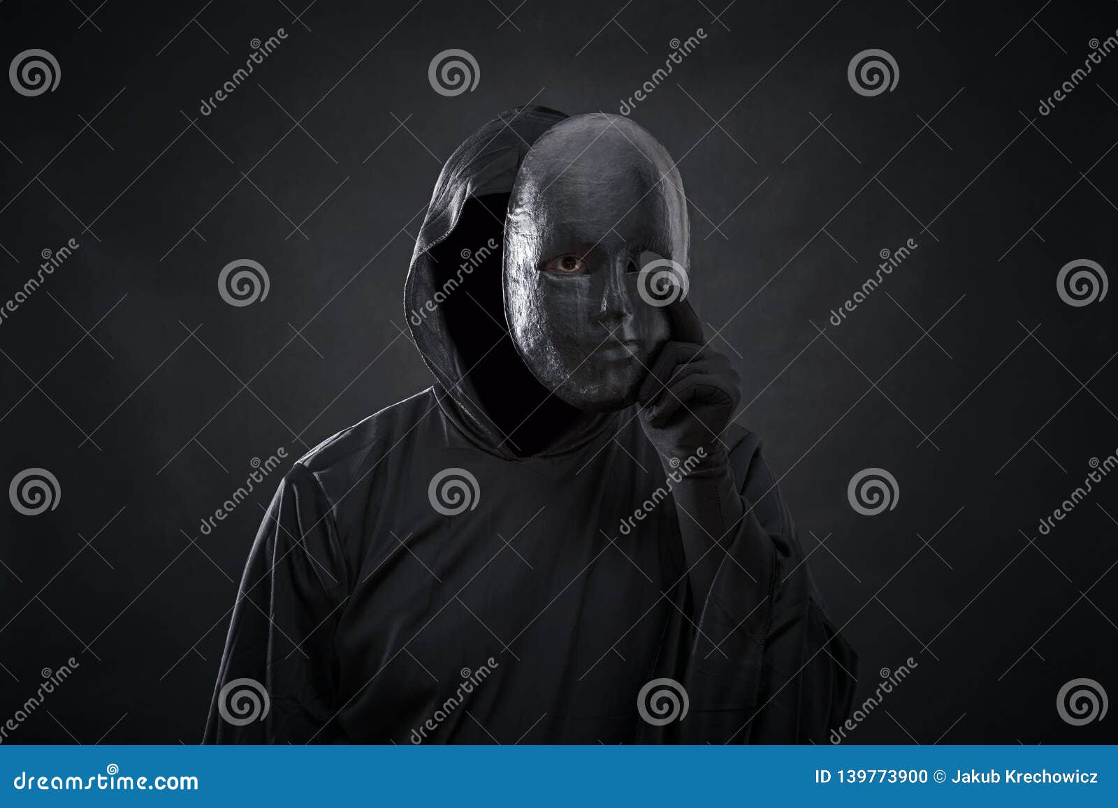 scary figure in hooded cloak with mask in hand