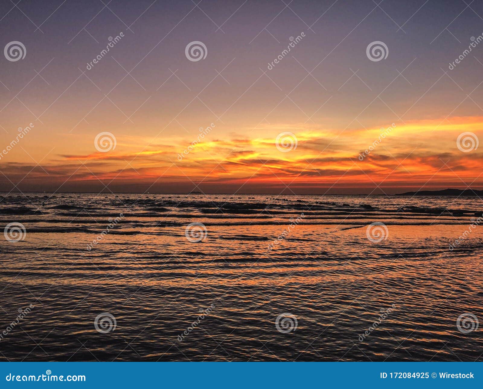 Scenery Of Sunset On The Beach With Calming Waves Of The Ocean Stock Scenery Of Sunset On The Beach With Calming Waves Of The Ocean Stock