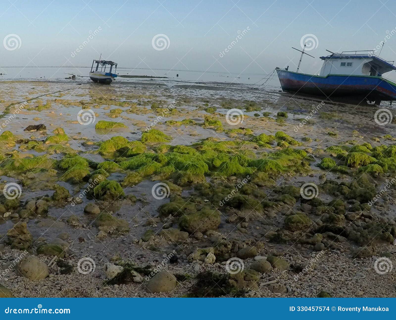 scenic fisherman boat on shore at dawn during low tide - serene morning coastal landscape